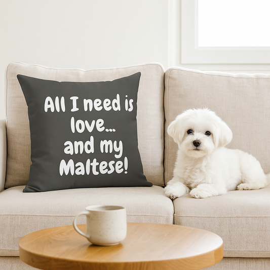 Grey pillow with white quote “All I need is love... and my Maltese!” on beige sofa next to a Maltese dog