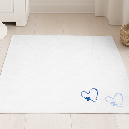 A white velveteen blanket with two blue heart and paw print designs, displayed in a minimal Scandinavian-style room.